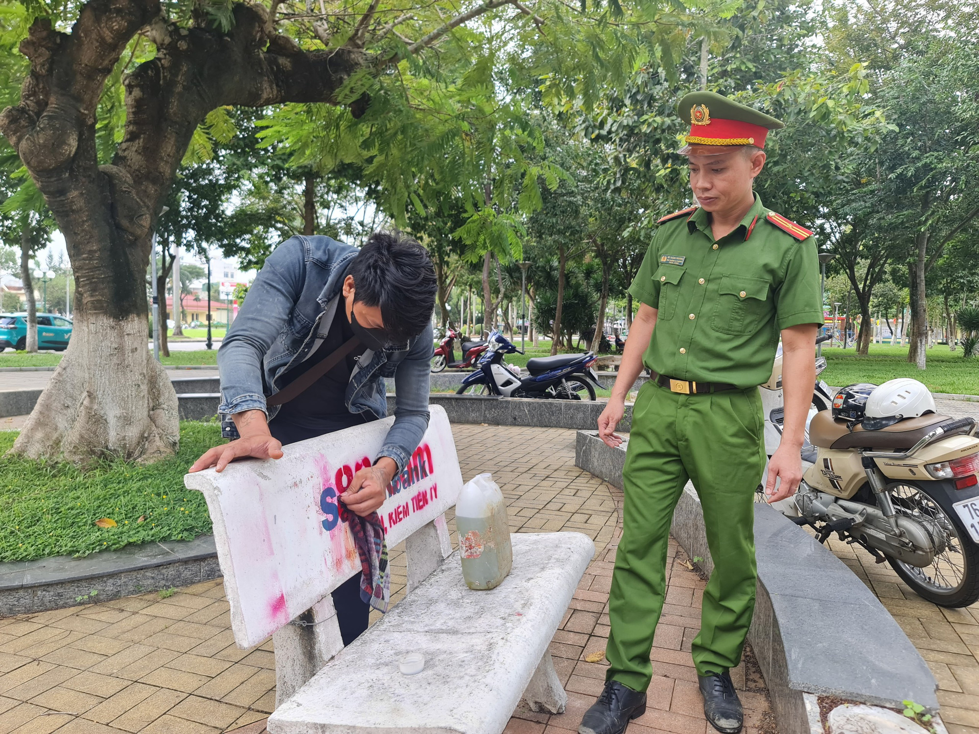 Thiếu tá Võ Thành Phương, phó trưởng Công an phường Nghĩa Chánh, trực tiếp theo dõi việc tẩy xóa web cá cược trên ghế đá - Ảnh: TRẦN MAI
